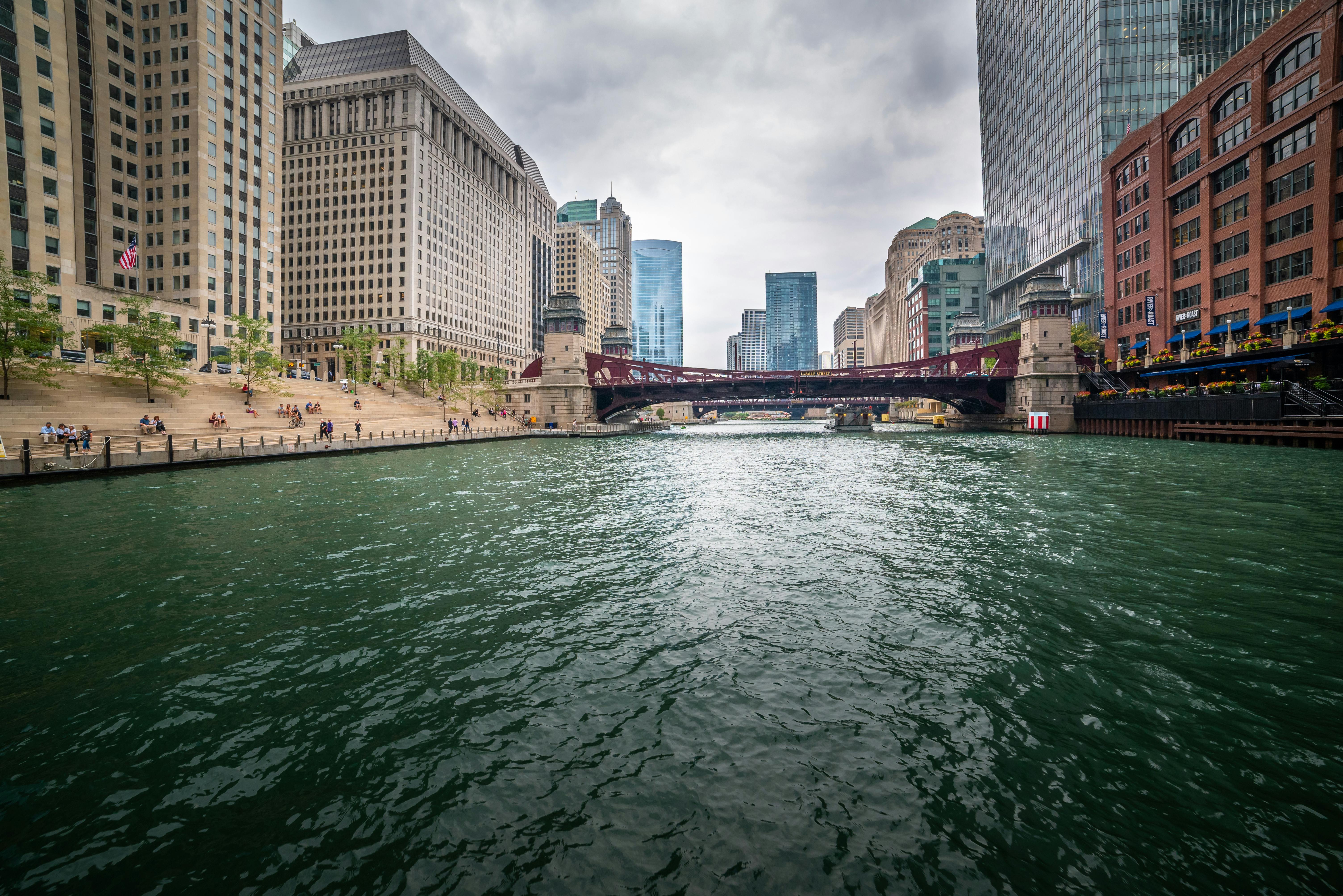 A breathtaking view of the Chicago River surrounded by iconic skyscrapers and a bridge on a cloudy day.