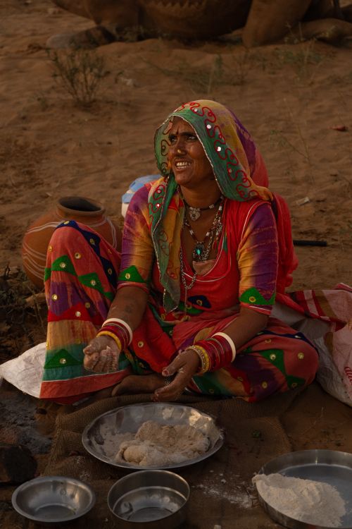 Free A vibrant depiction of an Indian woman in traditional attire preparing food outdoors. Stock Photo