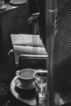 A serene cafe setting featuring a notebook, pen, coffee cup, and glass of water on a wooden table.