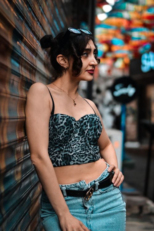 Free Fashionable woman in city scene wearing leopard print top and denim shorts, exuding urban style. Stock Photo