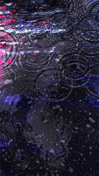 Vivid reflection of lights on a rainy street surface with ripples.