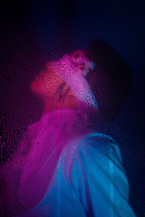 Free Artistic portrait featuring water droplets and purple light for a creative, moody effect. Stock Photo