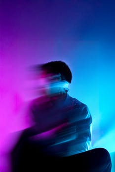 Blurred portrait of a male model in purple and blue lighting, creating an abstract effect.