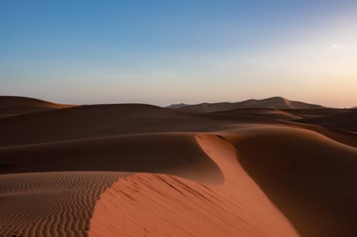 Free Tranquil desert sand dunes under a vibrant sunset sky, capturing natural beauty. Stock Photo