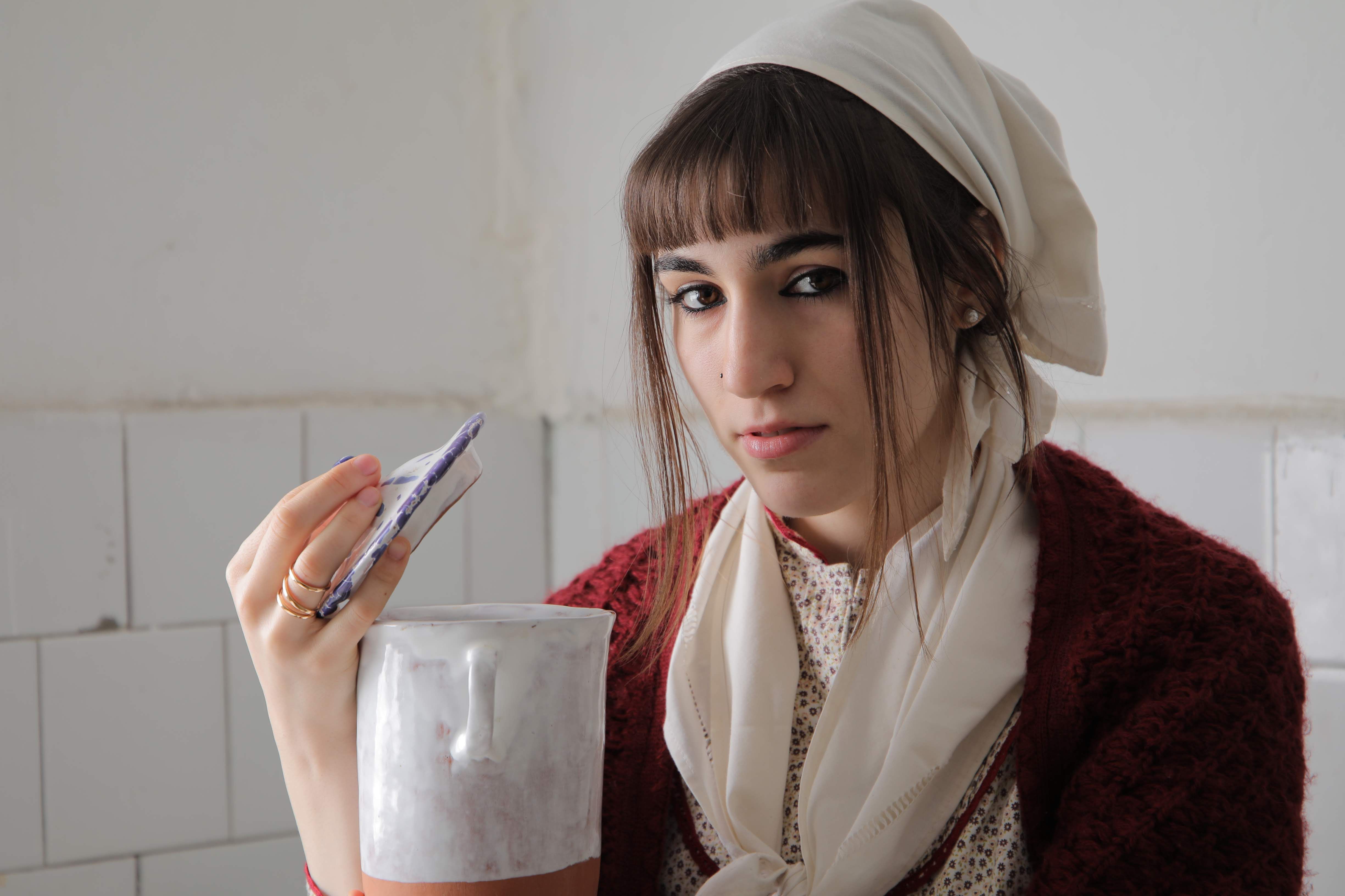 Portrait of a young woman with a ceramic object, artistic and focused.