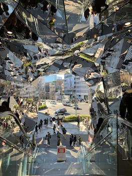 View of bustling city street through reflective glass kaleidoscope entry in Tokyo.