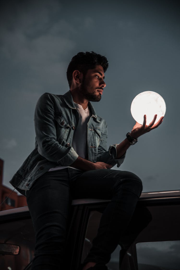 A Man Holding An Illuminated Model Of The Moon