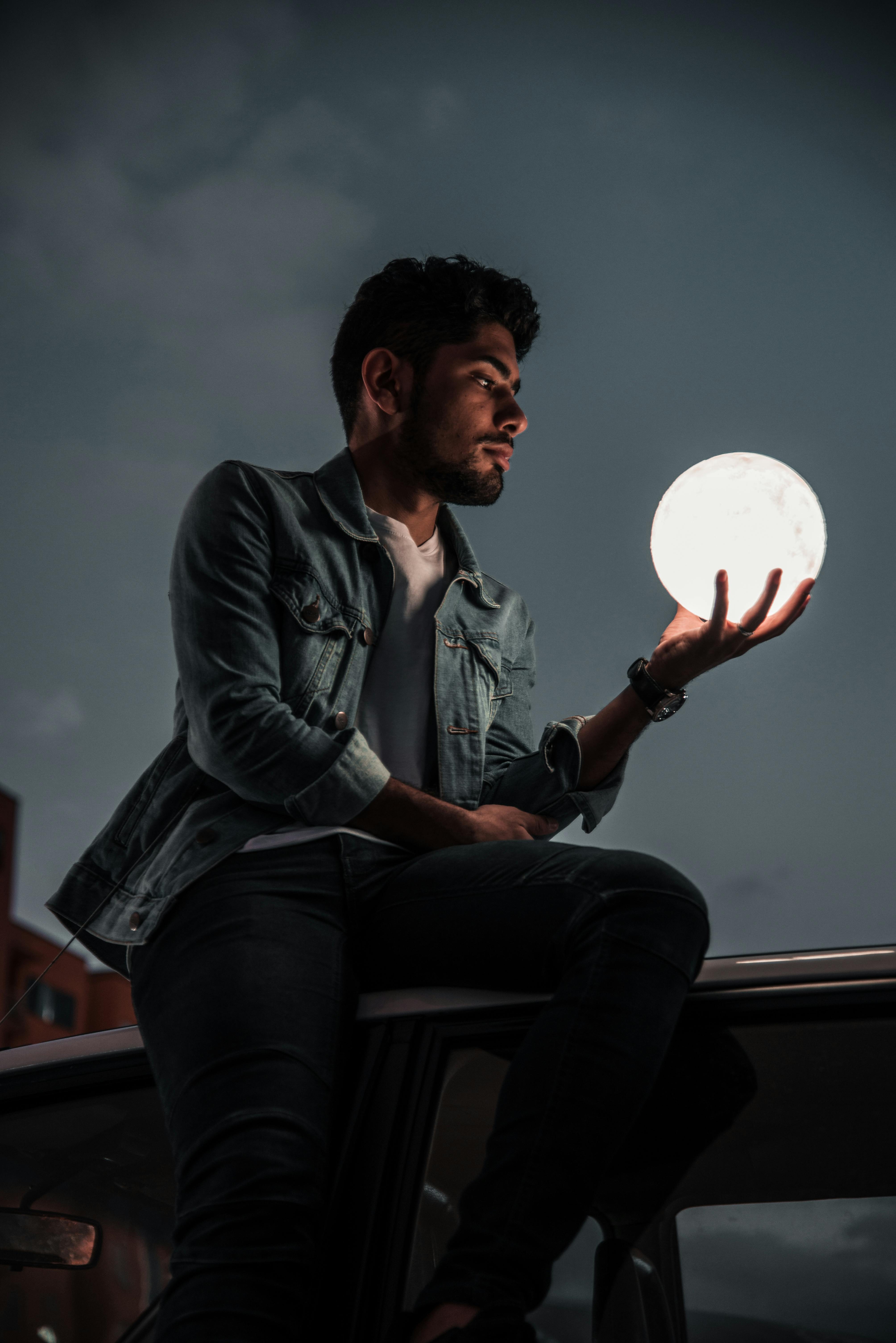 A Man Holding an Illuminated Model of the Moon · Free Stock Photo