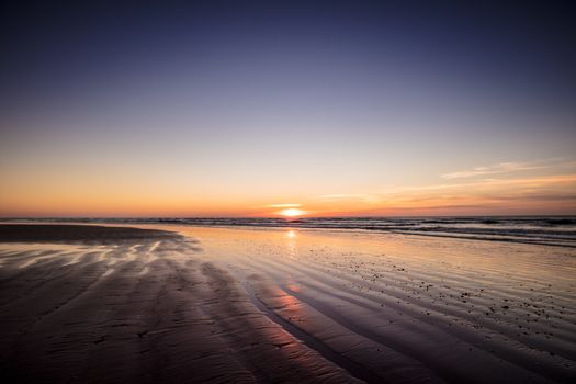 Tranquil sunset over Blackpool beach with calming waves and warm hues.
