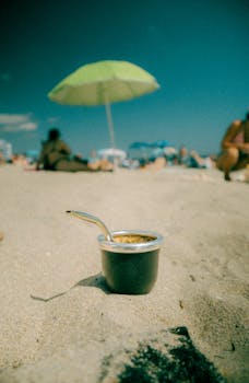 Relaxing beach scene at Miami Beach with coffee, umbrella, and sand.