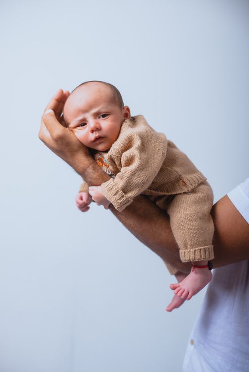 Gratis Padre sosteniendo amorosamente a un bebé recién nacido en un ambiente interior cálido, simbolizando el cuidado parental. Foto de stock