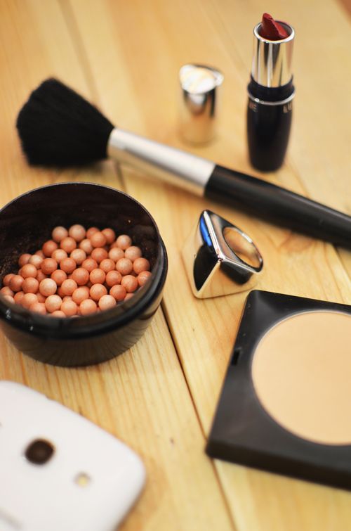 Free A stylish collection of makeup items arranged on a wooden table, including lipstick and brush. Stock Photo