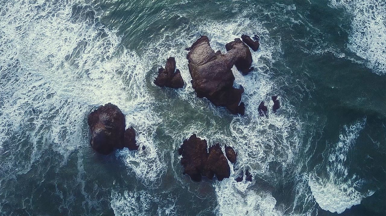 dynamic aerial view of ocean waves crashing against rocky structures c