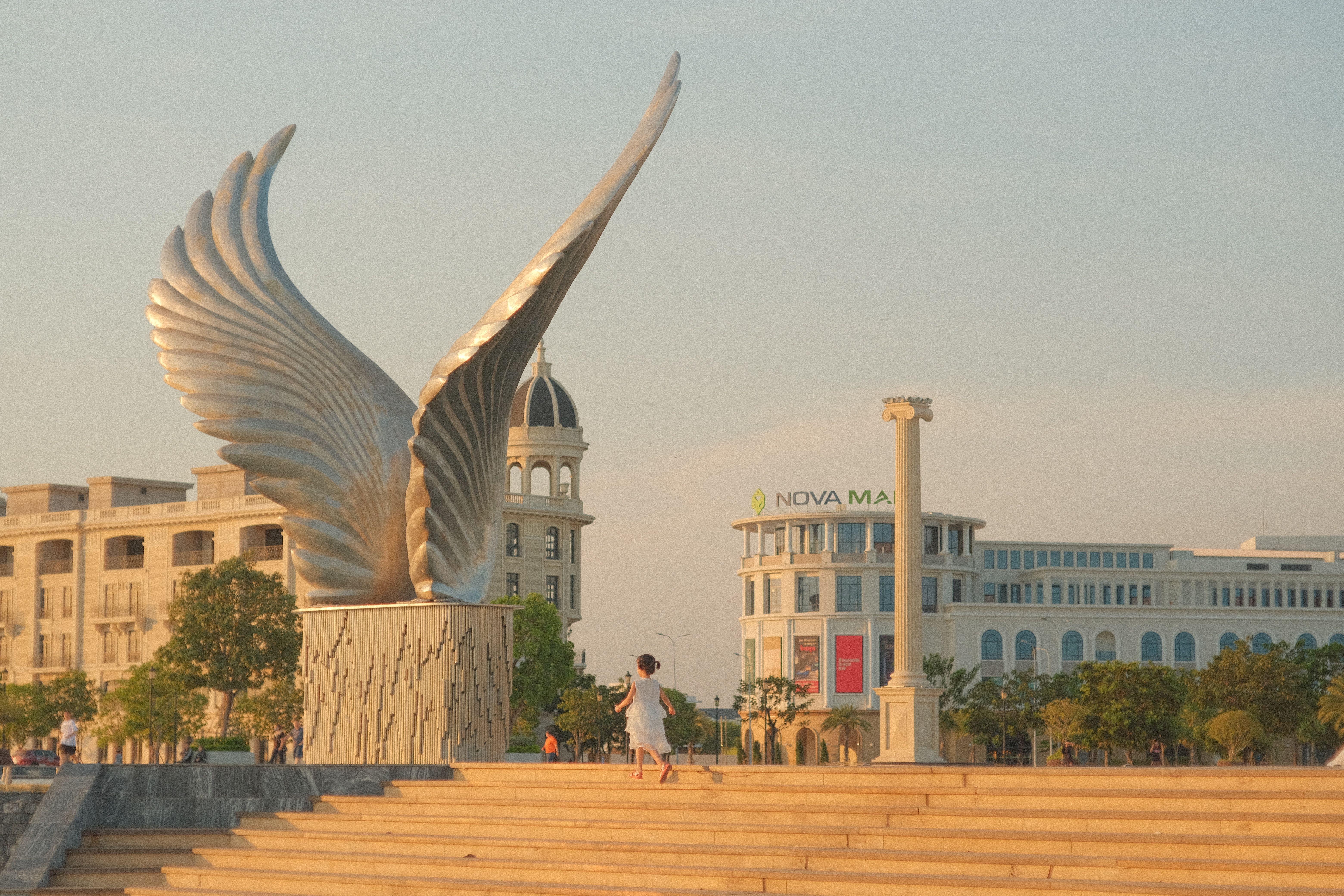 Elegant winged sculpture in a modern plaza with a calm atmosphere.