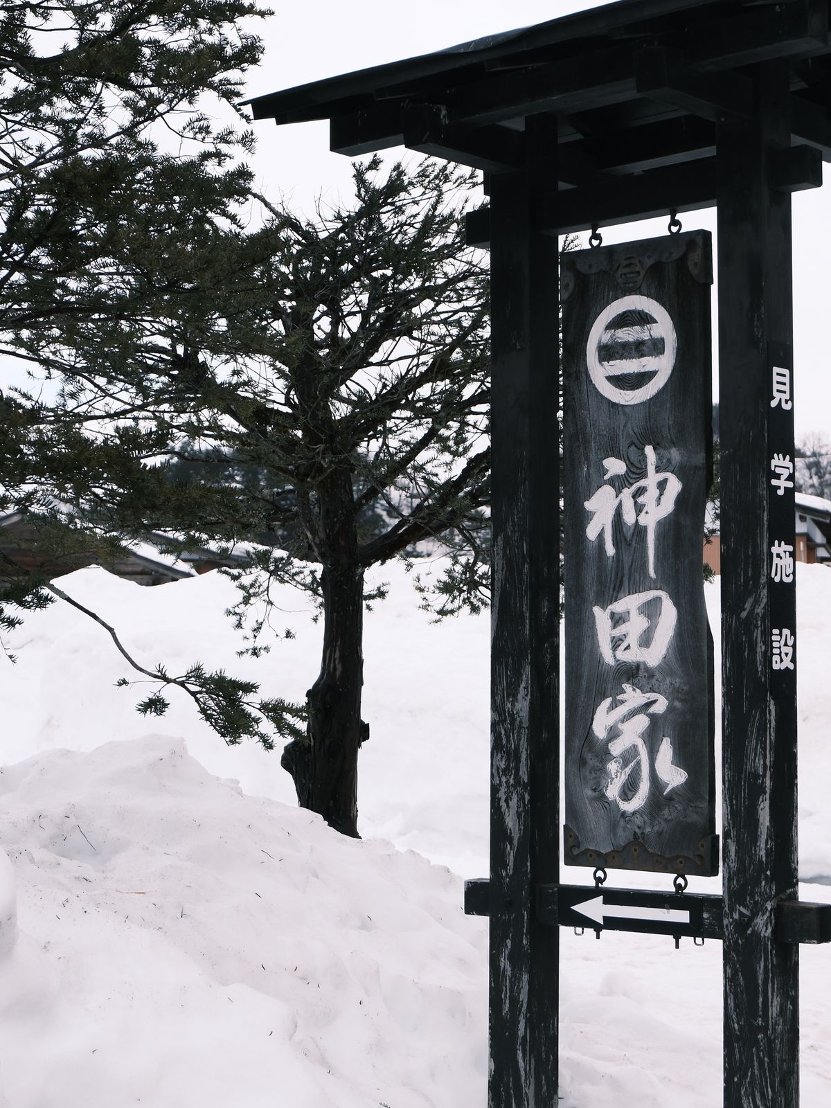 Traditional Japanese inn sign in heavy snow — a Takayama establishment in deep winter, Gifu Prefecture