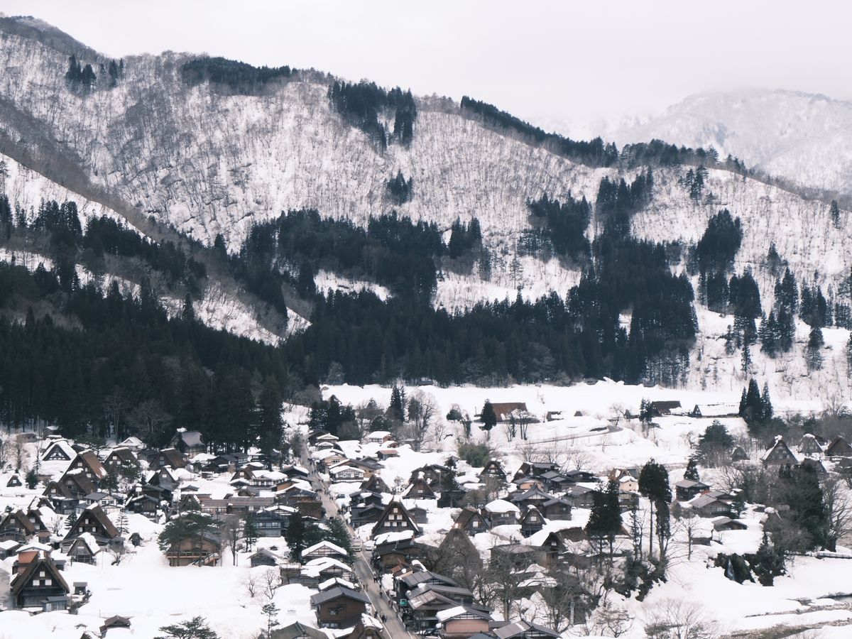 Wide view of Shirakawa-go village under snow — gassho farmhouses and surrounding mountains in deep winter, Gifu Prefecture