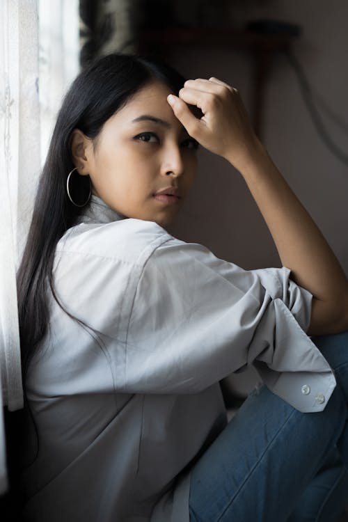 Side View Photo of Woman Sitting Beside Window Posing