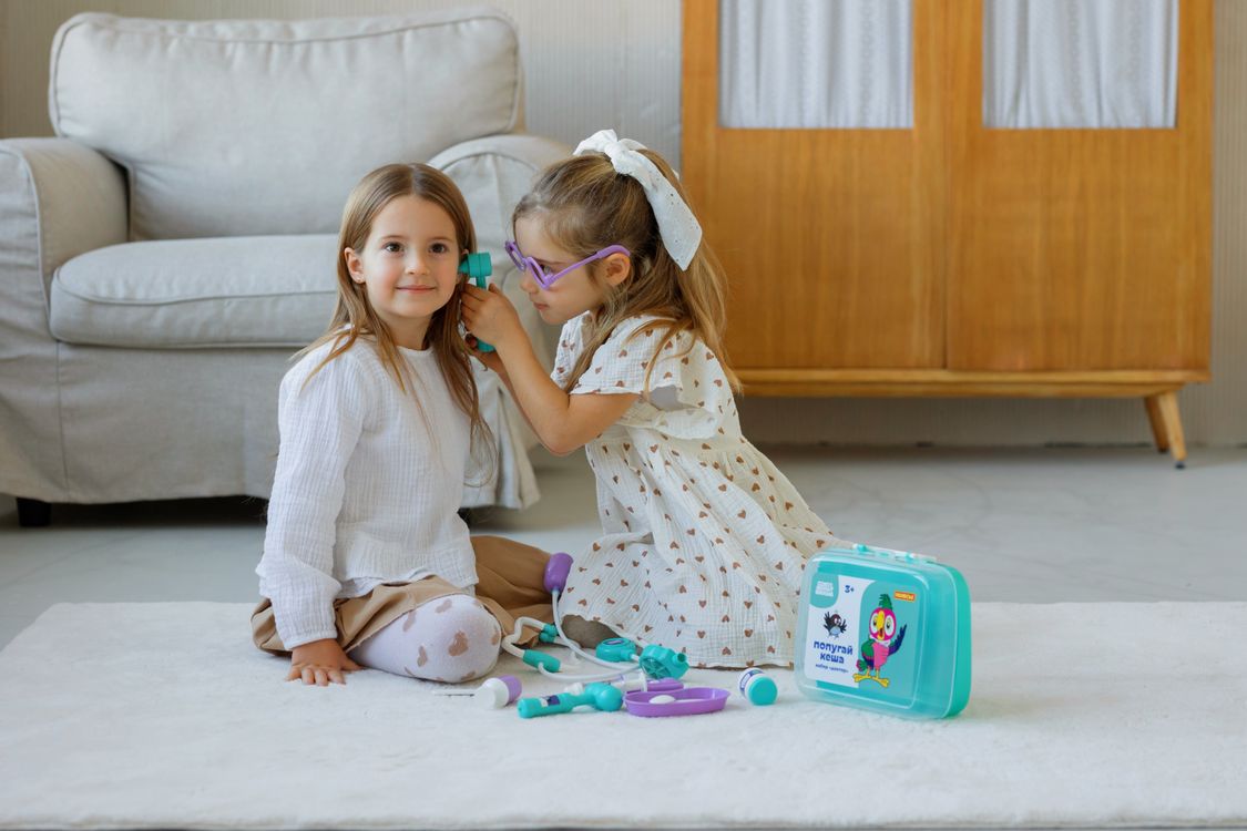 Free Two young girls play doctor with a toy medical kit in a cozy room setting. Stock Photo
