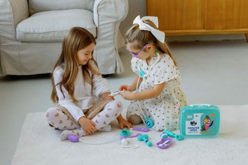 Free Two young girls engaged in a doctor role-play game indoors with toy medical kit. Stock Photo