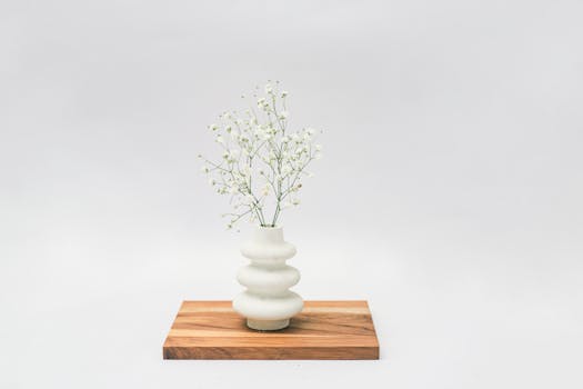 Beautiful baby's breath arrangement in a modern vase on wooden board. Minimalist decor with a soft, serene feel.