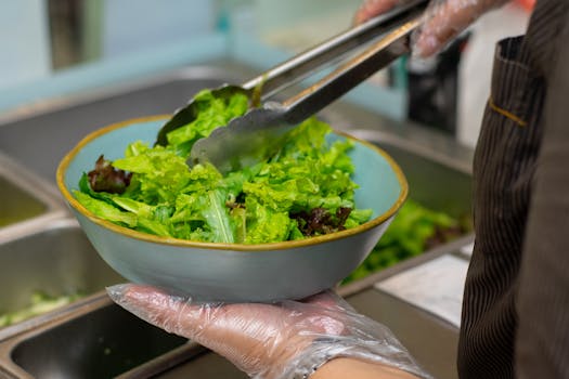A chef preparing a fresh green salad in a restaurant kitchen for a healthy meal.