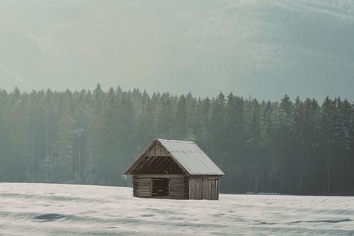 Free A serene winter scene with a rustic cabin in a snowy forest setting, perfect for invoking tranquility. Stock Photo