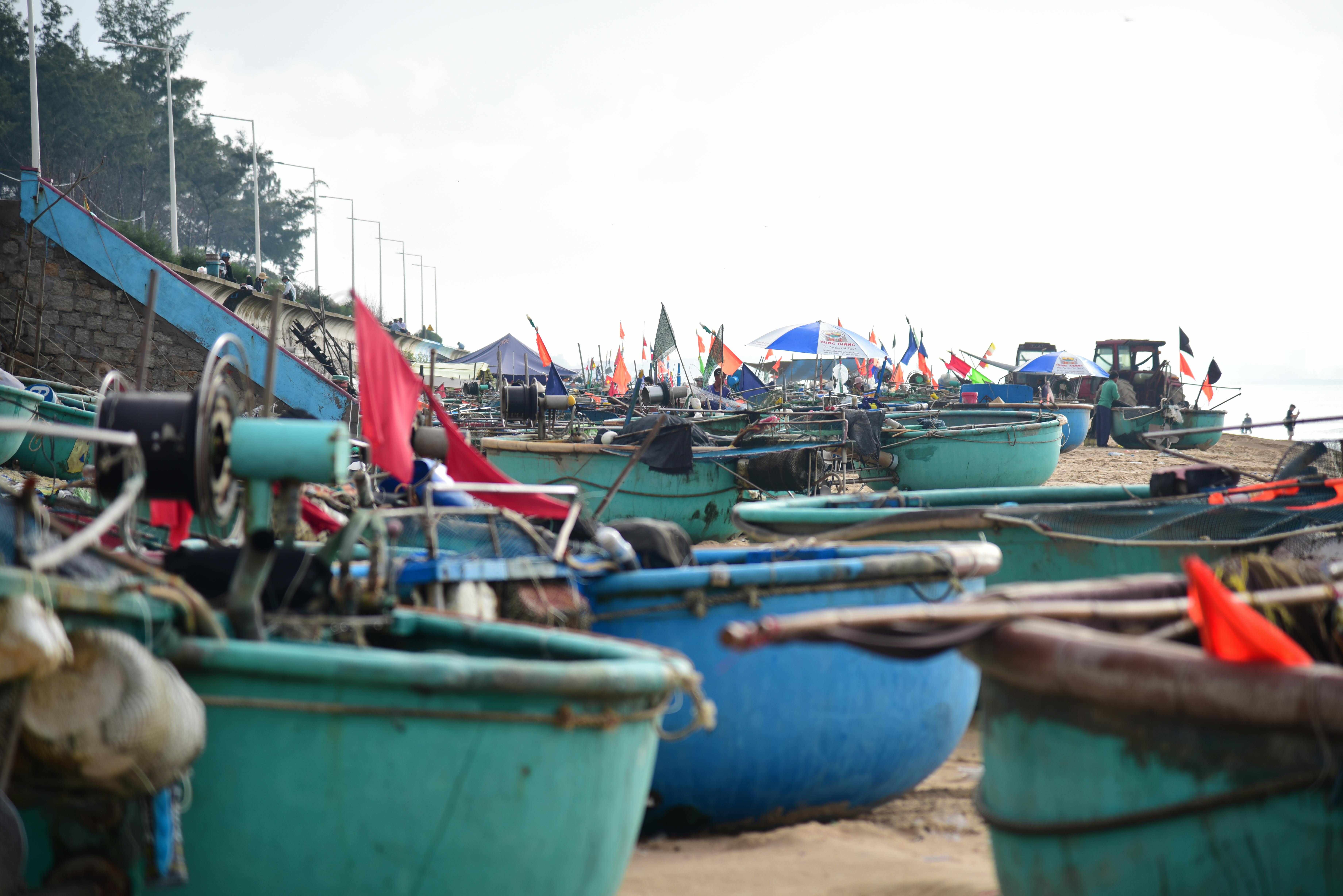 Colorful fishing boats on a beach with flags and equipment, ideal for travel themes.