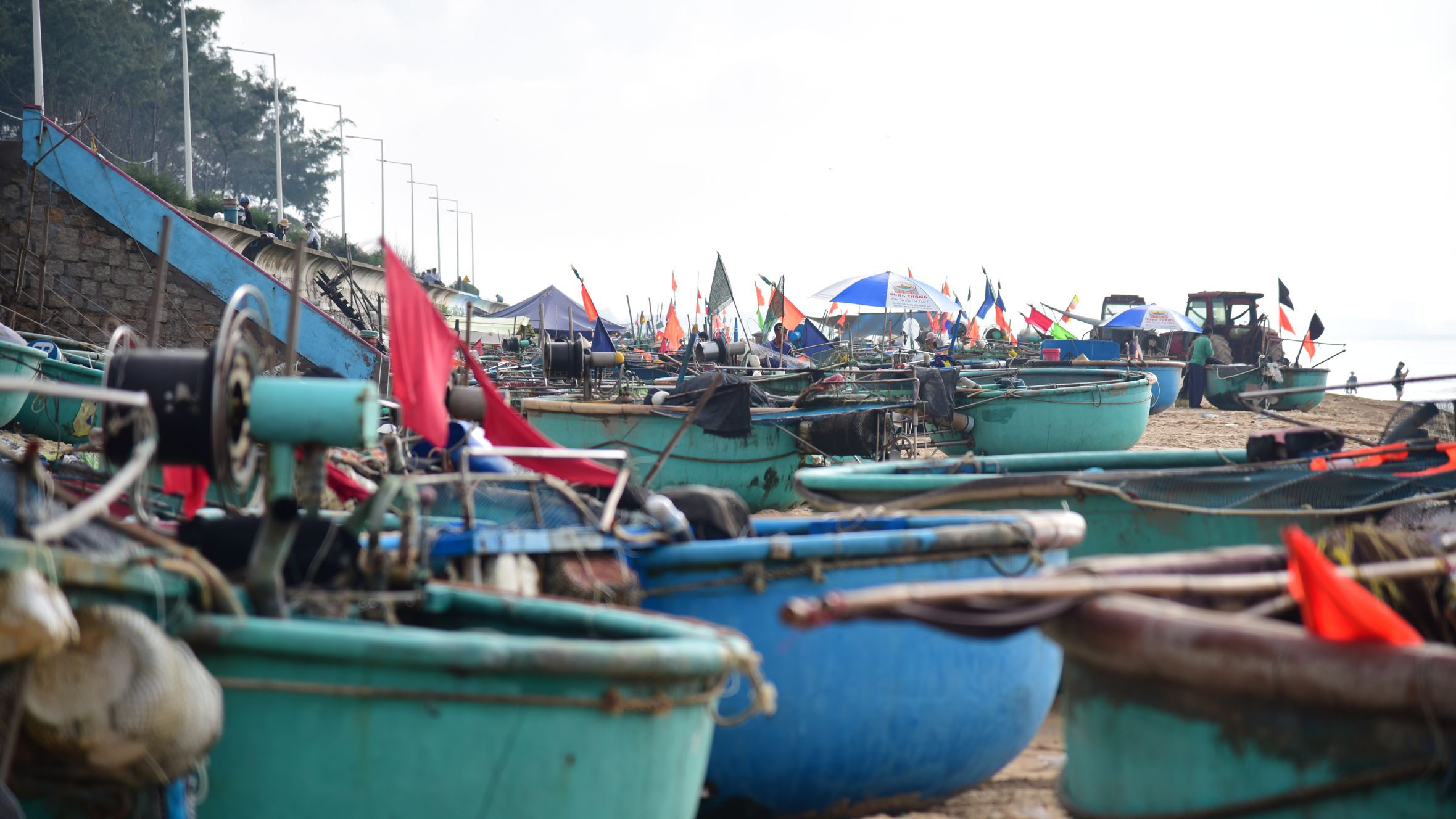 Colorful fishing boats on a beach with flags and equipment, ideal for travel themes.