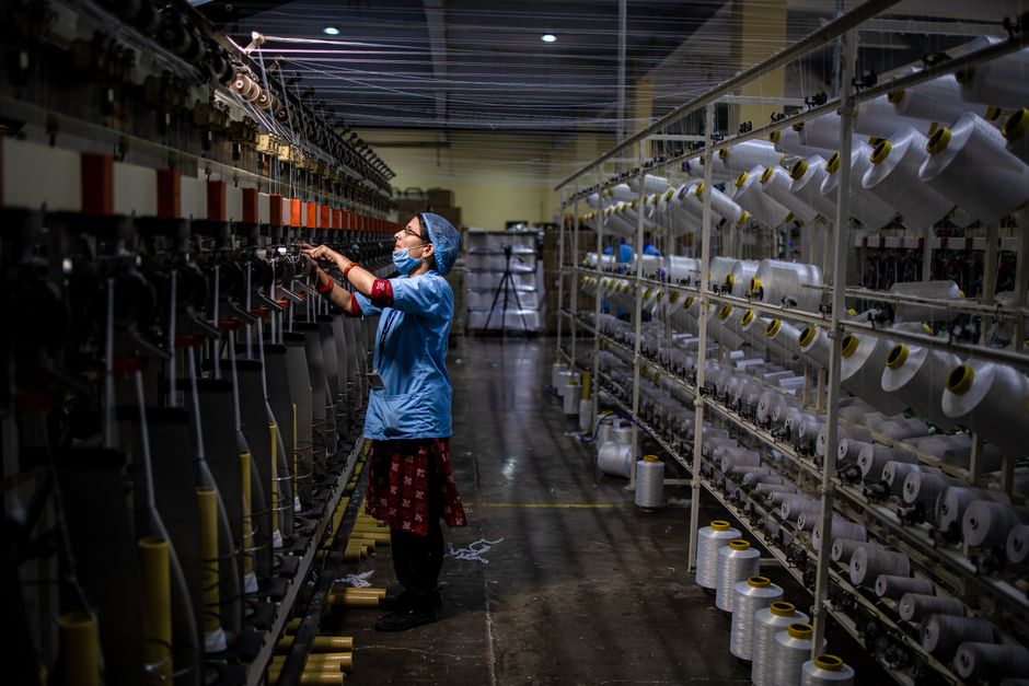Female worker in a textile factory managing machines, showcasing industrial manufacturing.