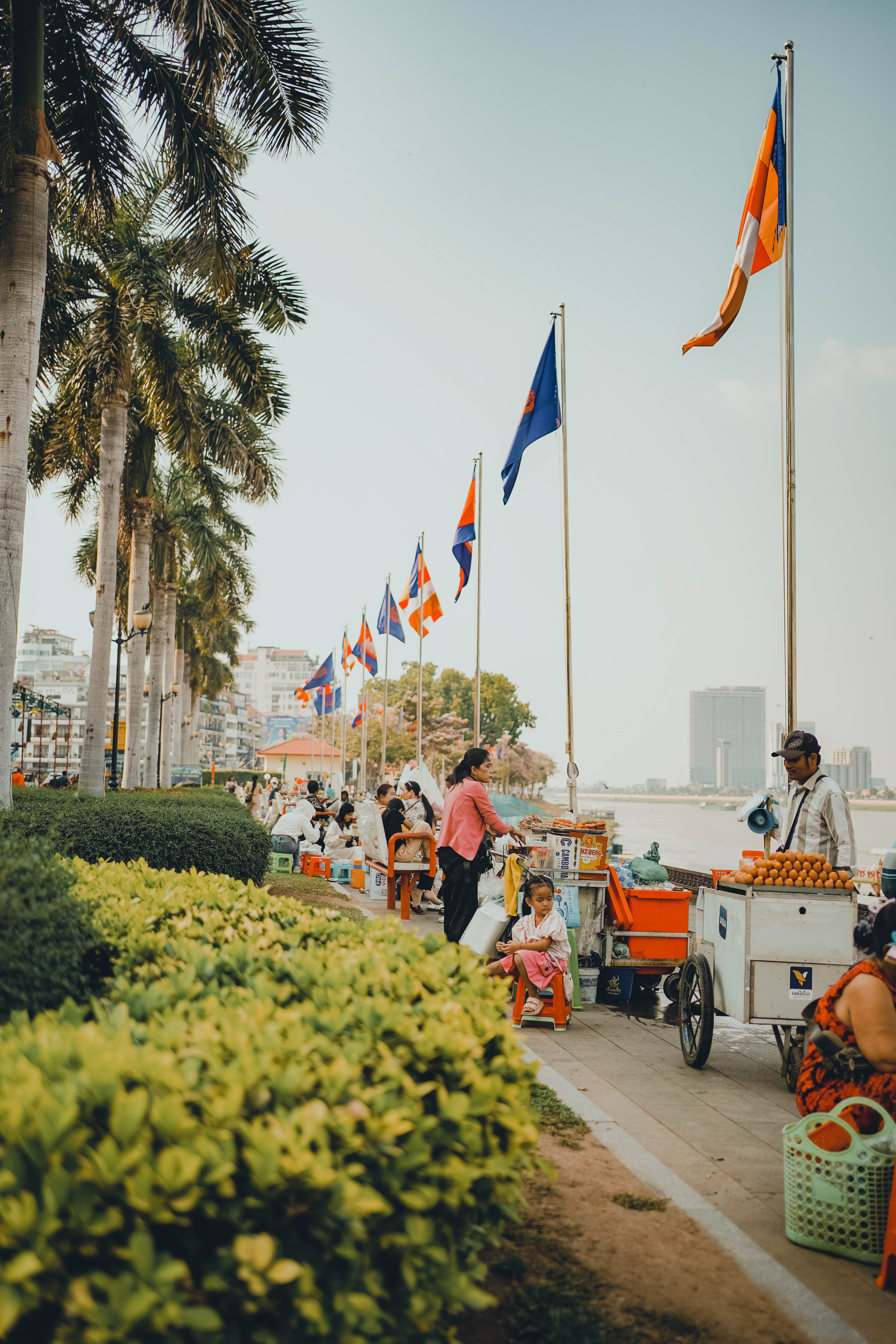 Paseo junto al río en Phnom Penh, Camboya, con banderas ondeando