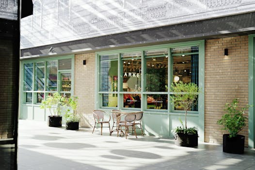 A cozy outdoor cafe setting with wicker chairs and potted plants against a stylish brick and glass facade.