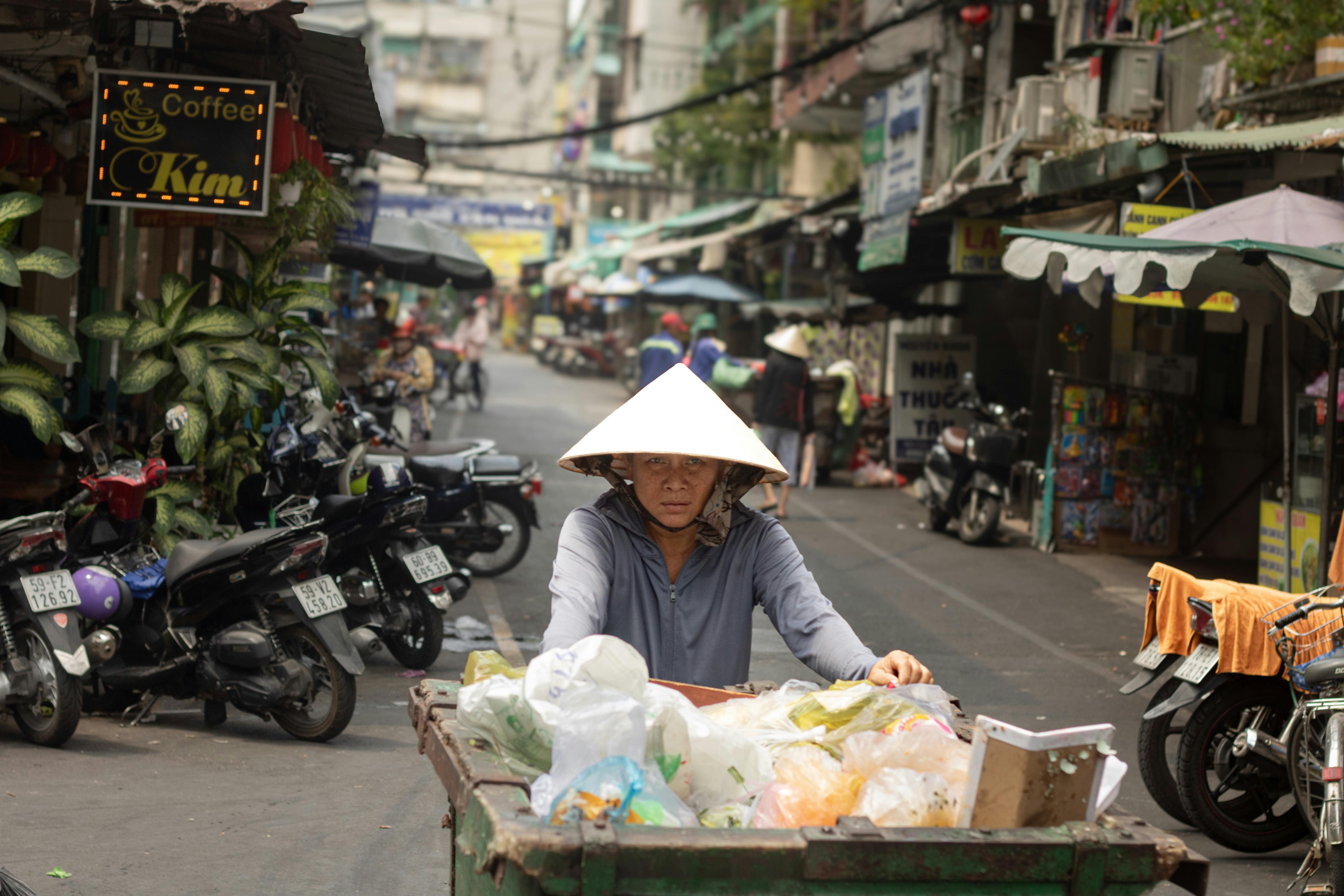 A street vendor in Hồ Chí Minh City pushes a cart through the bustling market, capturing vibrant urban life.