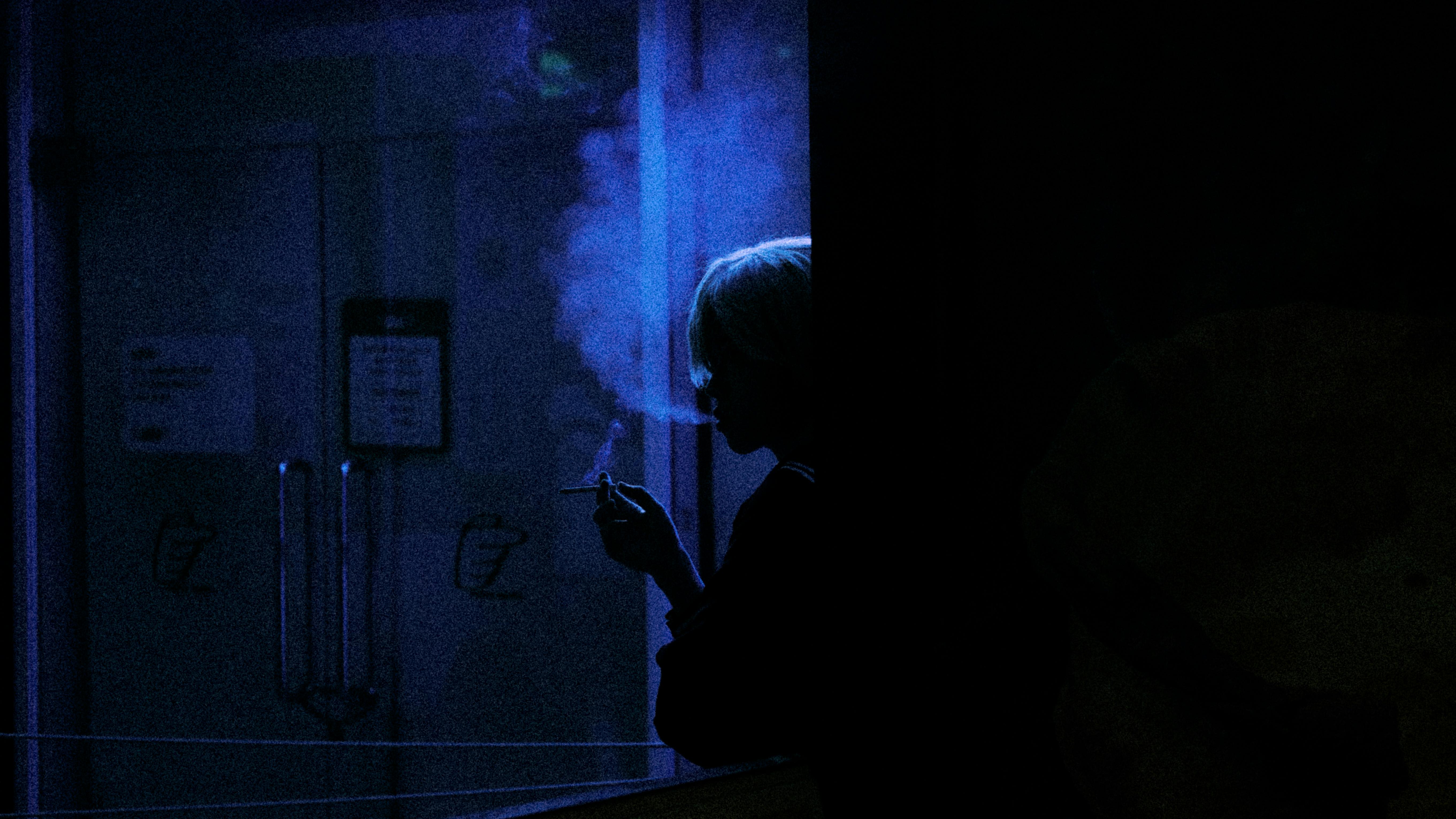 Kostenlos Silhouette einer rauchenden Person im Innenbereich mit blauem Umgebungslicht und Rauch. Stock-Foto