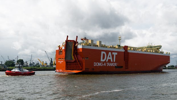 A large cargo ship in Hamburg port, Germany, with industrial cranes in the background.