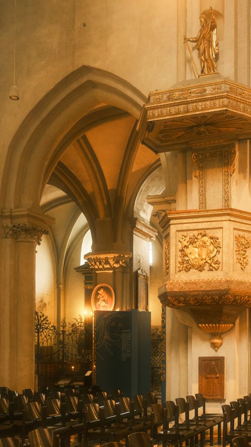 Free A beautifully lit historic church interior showcasing ornate religious architecture and seating. Stock Photo