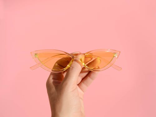 Человек, держащий оранжевые солнцезащитные очки