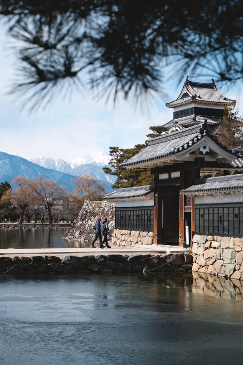 Free Matsumoto Castle in Japan with reflection on water and snowy mountains in the background. Stock Photo