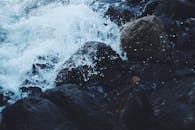 汹涌的海浪拍打着黑暗的岩石海岸，捕捉自然的律动