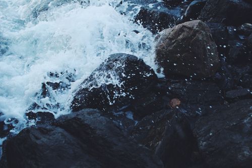 Free Powerful ocean waves splashing against dark coastal rocks, capturing natural motion. Stock Photo