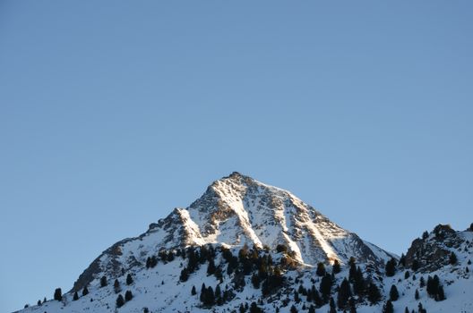 Snow-capped mountain peak against a clear blue sky in Valle d'Aosta, Italy.