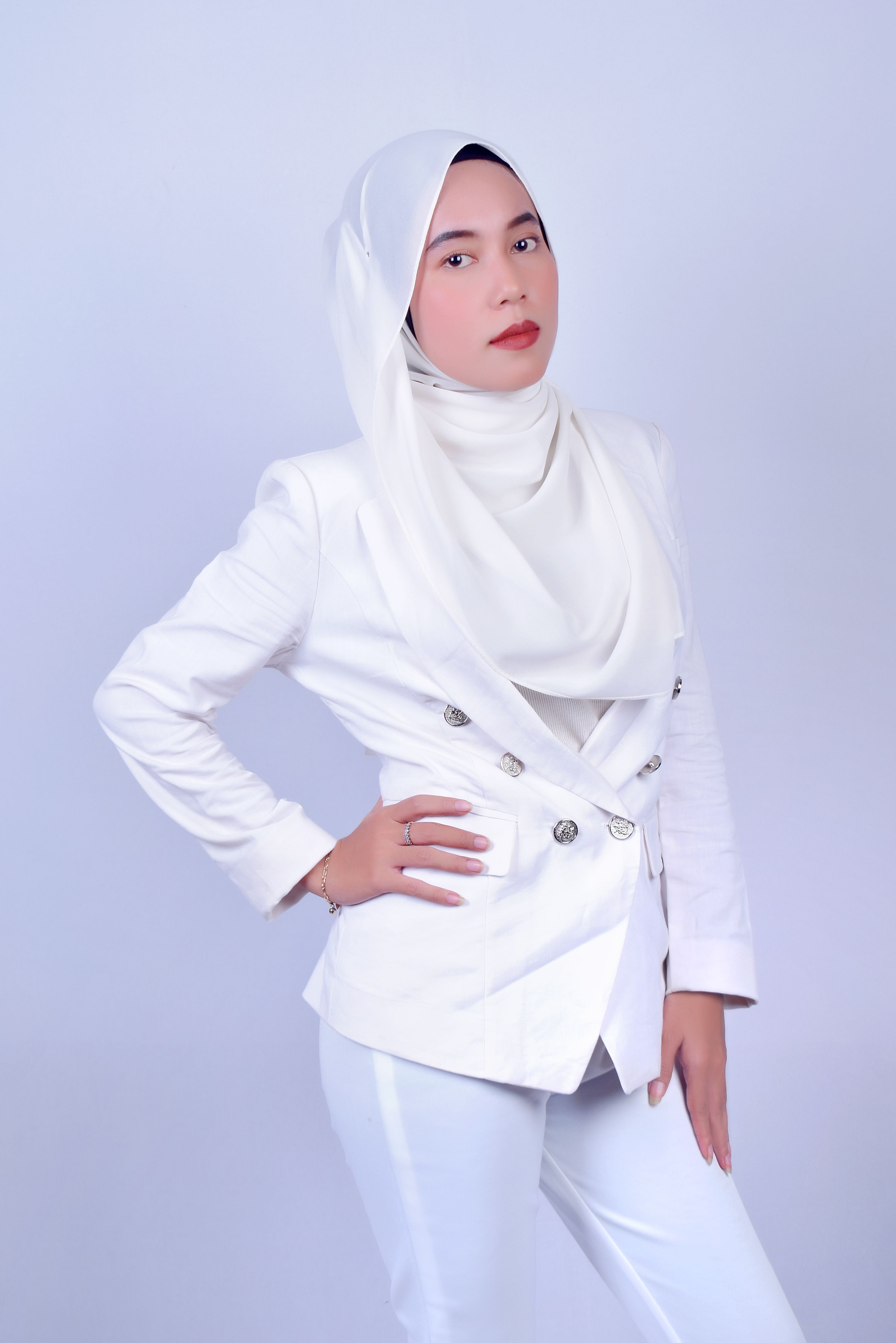 Portrait of a confident woman in a white hijab and suit, exuding empowerment and style.