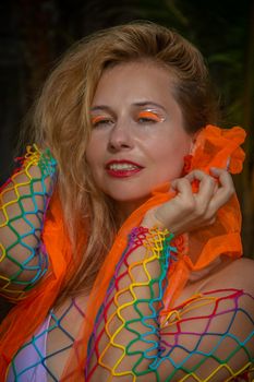 Vibrant portrait showing a woman with colorful makeup and a rainbow outfit against a dark backdrop.