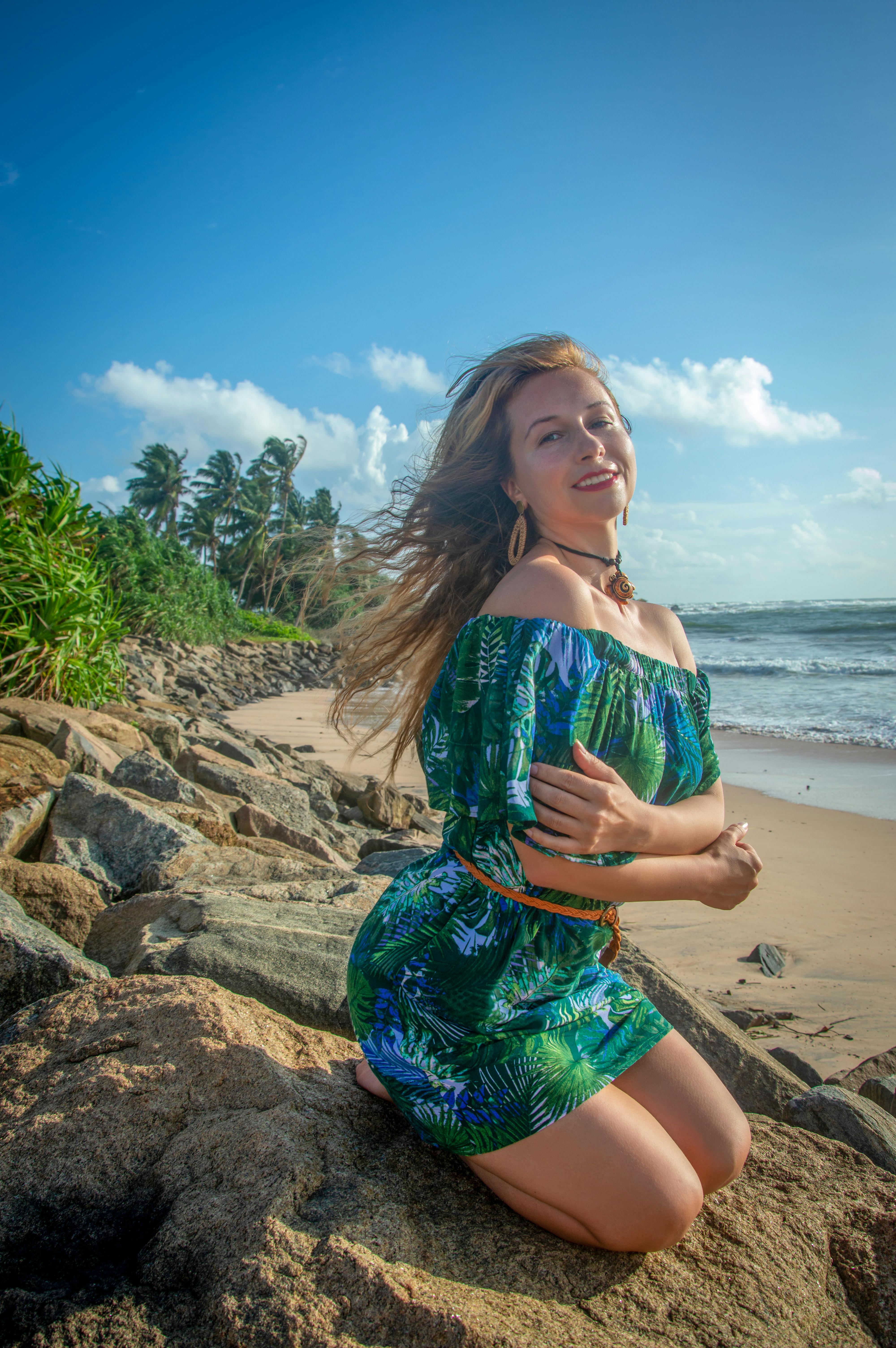 Woman in a floral dress enjoys a sunny day on a tropical beach with palm trees and ocean waves.