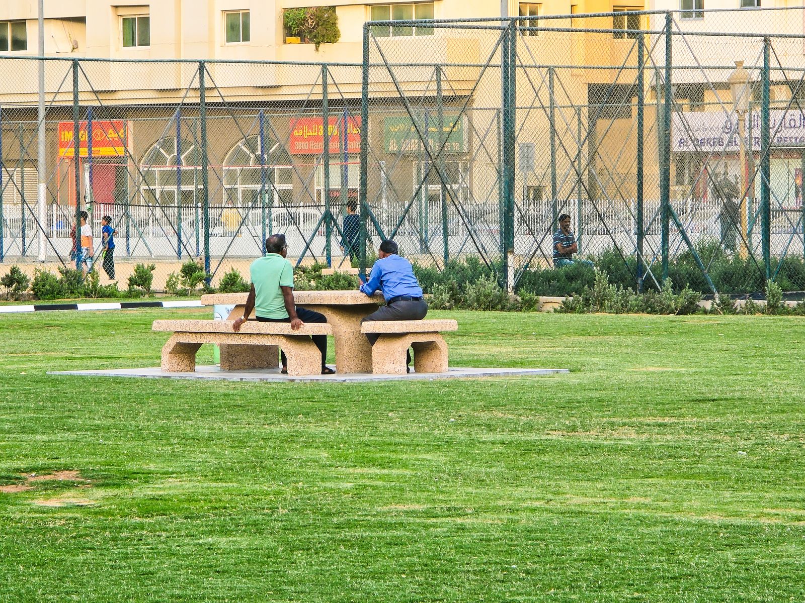 Residents at a picnic table on the green in a Dubai community park