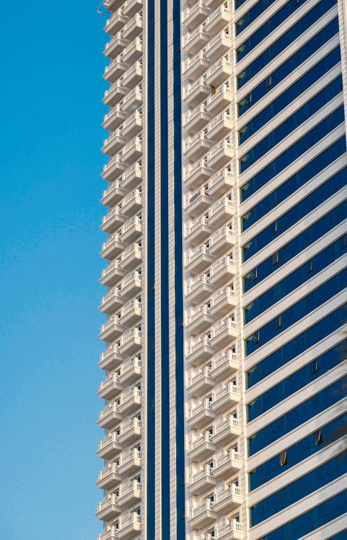 Free Architectural close-up of a modern skyscraper in Dubai set against a clear blue sky. Stock Photo