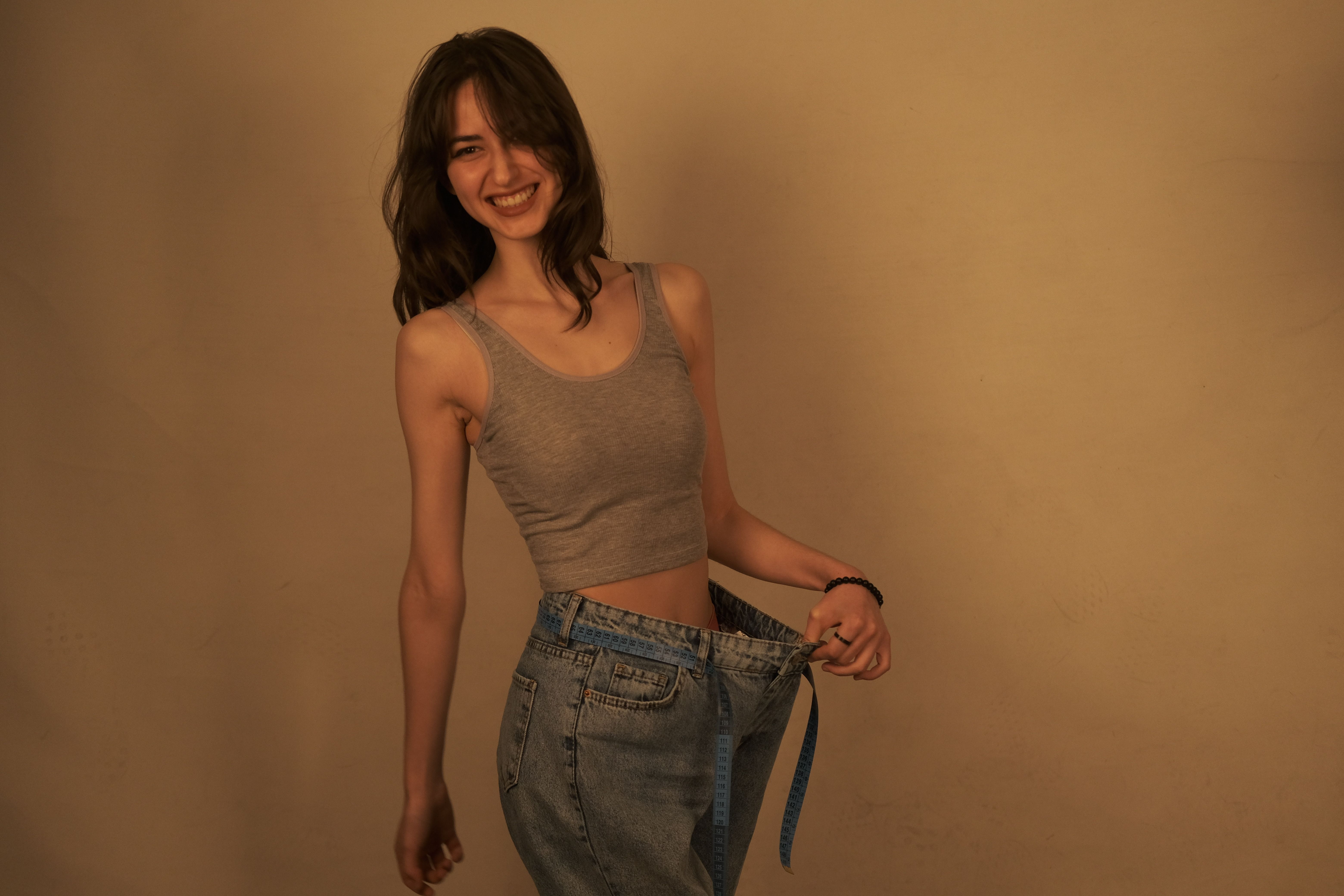 gratis Blijde vrouw toont succes in gewichtsverlies door het dragen van losse jeans. Gezond levensstijlconcept. Stockfoto
