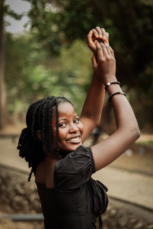 Free Smiling woman with braided hair enjoying a moment outdoors in nature, dressed in black. Stock Photo
