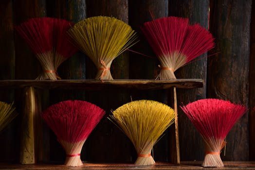 Vibrant incense stick bundles in red and yellow on a rustic wooden shelf.