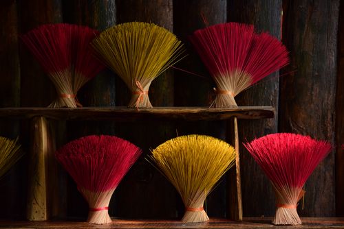 Free Vibrant incense stick bundles in red and yellow on a rustic wooden shelf. Stock Photo