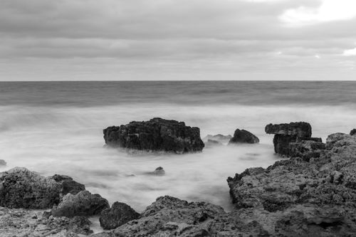 Free Moody black and white seascape capturing dramatic ocean rocks and waves. Stock Photo